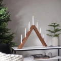 Drewniany świecznik LED o trójkątnej formie z siedmioma białymi świecami, ustawiony na konsoli w świątecznej aranżacji z choinką.