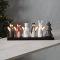 Dekoracyjny świecznik z figurkami leśnych zwierząt, jelonka, lisa, niedźwiedzia, sowy i królika, ustawiony na jasnym stole obok choinki.