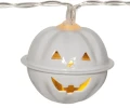 Biała lampka w formie dyni Halloween z podświetlanymi wycięciami, pokazana z bliska na jasnym tle jako element łańcucha świetlnego.