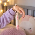 Różowa latarka w kształcie jednorożca zawieszona na nadgarstku za elastyczną pętelkę, pokazana z widocznym przyciskiem włączania.
