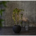Lampki choinkowe LED 160 diod białe ciepłe, oplecione wokół rośliny doniczkowej w nowoczesnym wnętrzu, przewód czarny, oświetlenie bateryjne z timerem.