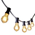Girlanda ogrodowa z czarnym przewodem i żarówkami LED TA60 2,5W 2000K z serii Decoled Amber, zawieszona w łuku. Żarówki w bursztynowym szkle emitują dekoracyjne, ciepłe światło z widocznym spiralnym żarnikiem.