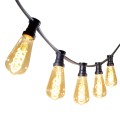Girlanda ogrodowa z czarnym przewodem i żarówkami LED ST64 3,2W 2100K z serii Decoled Amber, zawieszona w łuku. Żarówki w bursztynowym szkle emitują dekoracyjne, ciepłe światło z widocznym spiralnym żarnikiem.