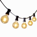 Zbliżenie na girlandę świetlną z żarówkami G80 LED o ciepłej barwie światła. Czarny przewód i oprawki kontrastują z białym tłem, a złocisty blask żarówek tworzy dekoracyjny, nastrojowy efekt.