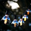 Żarówki LED Filament G125 zamontowane w girlandzie plenerowej, dymione szkło i spiralne filamenty w ciepłej barwie światła.