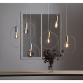 Lampa wisząca SHAPE z cylindryczną złotą oprawką i pionową owalną ramą wokół źródła światła.