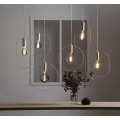 Lampa wisząca SHAPE z cylindryczną złotą oprawką i zaokrągloną prostokątną ramą wokół żarówki.