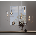 Lampa wisząca SHAPE z cylindryczną złotą oprawką i zaokrągloną prostokątną ramą wokół żarówki.