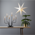 Lampa stołowa z żarówkami LED ustawiona na drewnianym stole obok dekoracyjnej gwiazdy i rośliny. Ciepłe światło podkreśla świąteczny charakter aranżacji.