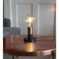 Mała lampka stołowa z czarną podstawą i żarówką LED E27 G95 filament na drewnianym blacie.