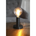 Mała lampka stołowa z czarną podstawą i żarówką LED E27 G95 filament na drewnianym blacie.