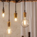 Dekoracyjne żarówki LED filament w różnych kształtach zamontowane w mosiężnych oprawkach wiszących nad stołem jadalnianym. Ciepłe światło tworzy przytulną atmosferę wnętrza w stylu vintage.