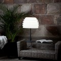 Lampa stołowa ogrodowa RHODOS z czarną smukłą podstawą i jasnym kloszem złożonym z poziomych warstw.