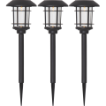 Trzy czarne solarne lampy ogrodowe z przezroczystymi kloszami osłoniętymi kratką, osadzone na szpilkach, przedstawione na białym tle.