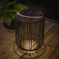 Duży lampion solarny LED z czarną metalową obudową i jutowym uchwytem ustawiony na drewnianym tarasie po zmroku.