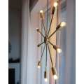 Lampa wisząca PIX o średnicy 50 cm w kolorze mosiądzu, z promieniście rozchodzącymi się ramionami zakończonymi świecącymi żarówkami.