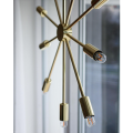 Lampa wisząca PIX o średnicy 50 cm w kolorze mosiądzu, z promieniście rozchodzącymi się ramionami zakończonymi świecącymi żarówkami.