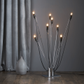 Nowoczesna lampa podłogowa z wieloma ramionami i żarówkami LED E14 T26 na tle szarej zasłony.