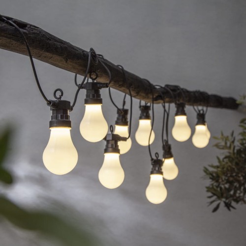 Girlanda ogrodowa LED z mlecznymi kloszami zawieszona na drewnianej belce, emitująca ciepłe, nastrojowe światło, idealna do oświetlenia tarasu lub altany.
