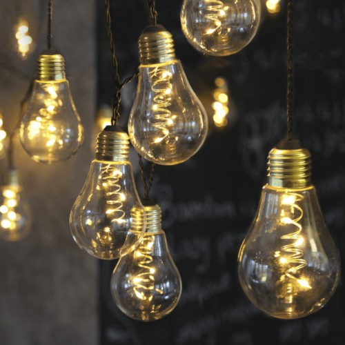 Zbliżenie na girlandę LED z przezroczystymi kloszami i spiralnymi mikro diodami Dew Drop, emitującą ciepłe, nastrojowe światło na ciemnym tle.