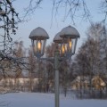 Stylowa latarnia ogrodowa z dekoracyjnymi żarówkami LED filament pokryta śniegiem w zimowym krajobrazie.