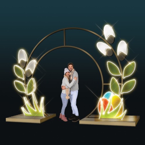 Brama Wielkanocna 3D LED w formie okręgu z podświetlanymi liśćmi i pisankami, dekoracja świetlna do sesji zdjęciowych, przestrzenna konstrukcja z EKO LED, scena z parą stojącą wewnątrz instalacji.