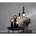 Lampa stołowa TUB z czarnym walcowym korpusem i widocznym źródłem światła osadzonym bez klosza.