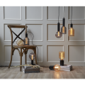 Minimalistyczna lampa TUB z wysoką czarną podstawą w kształcie cylindra i dekoracyjną żarówką.