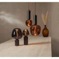 Minimalistyczna lampa TUB z wysoką czarną podstawą w kształcie cylindra i dekoracyjną żarówką.