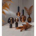Minimalistyczna lampa TUB z wysoką czarną podstawą w kształcie cylindra i dekoracyjną żarówką.