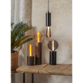 Minimalistyczna lampa TUB z wysoką czarną podstawą w kształcie cylindra i dekoracyjną żarówką.