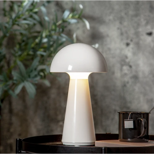 Biała lampa stołowa ogrodowa LED MUSHROOM akumulatorowa z USB IP44, ustawiona na stoliku w nowoczesnym wnętrzu.