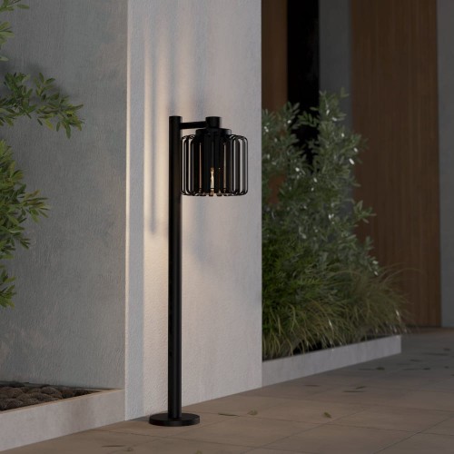 Lampa ogrodowa SELINUS z wysokim czarnym słupkiem i bocznie osadzonym ażurowym kloszem.
