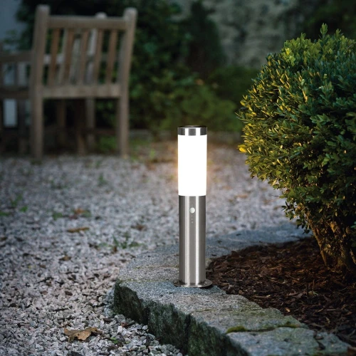 Lampa ogrodowa HELSINKI z cylindrycznym metalowym korpusem, jasnym kloszem i czujnikiem ruchu.