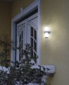 Świecący kinkiet BEVERLY E27 IP44 zamontowany na ścianie budynku, przeznaczony do użytku zewnętrznego.