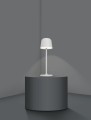 Kompaktowa biała lampa LED z abażurowym kloszem ustawiona na ciemnym stoliku.