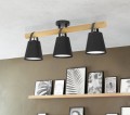 Nad półką z ramkami zamontowano lampę sufitową BOYLE z trzema czarnymi metalowymi kloszami rozmieszczonymi wzdłuż drewnianej belki.