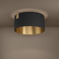 Czarna lampa ścienna LED o zaokrąglonej formie ze złotym wnętrzem, zamontowana na jasnej ścianie i emitująca światło w dół.