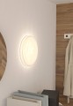W jasnym wnętrzu lampa sufitowa BATTISTONA emituje ciepłą poświatę, podkreślając okrągły kształt białej oprawy na ścianie.