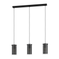 Lampa wisząca PINTO TEXTIL 1 z trzema cylindrycznymi kloszami ze szkła i czarnej tkaniny, zawieszonymi na przewodach pod podłużną podsufitką.