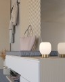 Na jasnej komodzie lampa stołowa MANZANARES tworzy dekoracyjny akcent dzięki białemu szklanemu kloszowi i podstawie w kolorze mosiądzu.
