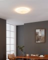 W jasnym pokoju lampa sufitowa LED NIEVES 1 rozświetla dekoracyjny klosz, tworząc na suficie ciepłą białą poświatę o barwie 3000K.