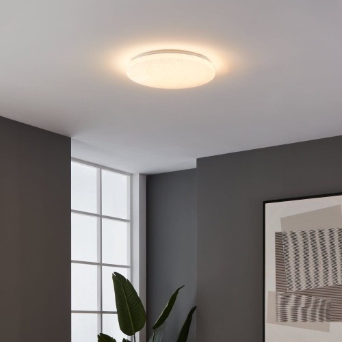Okrągła lampa sufitowa LED RENDE 19,5W zamontowana w nowoczesnym wnętrzu, emitująca ciepłe białe światło 3000K.