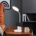 Lampa stołowa LED BROLINI z białą smukłą konstrukcją i wygiętym ramieniem, ustawiona na stoliku i emitująca światło w dół.
