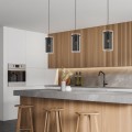 Lampa wisząca PINTO TEXTIL 1 z trzema smukłymi kloszami zawieszonymi nad wyspą kuchenną w jasnym, nowoczesnym wnętrzu.