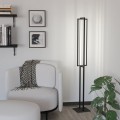 Lampa podłogowa LED SIBERIA 34W o smukłej czarnej konstrukcji, ustawiona w nowoczesnym salonie obok sofy i rośliny.