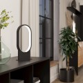 Lampa stołowa LED CODRIALES 10,8W z czarną metalową podstawą i owalnym elementem świetlnym, ustawiona na komodzie w nowoczesnym wnętrzu.