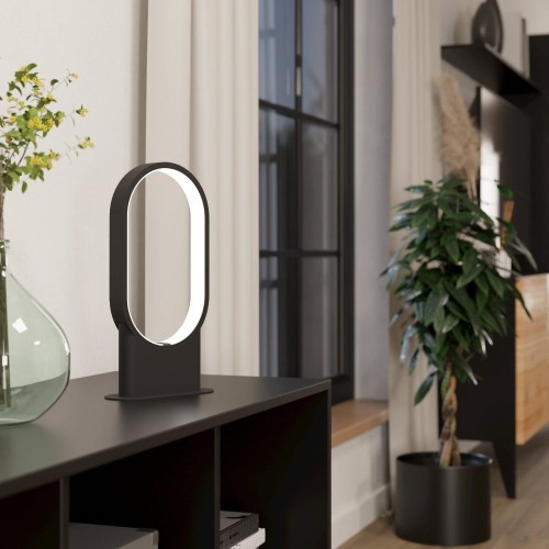 Lampa stołowa LED CODRIALES 10,8W z czarną metalową podstawą i owalnym elementem świetlnym, ustawiona na komodzie w nowoczesnym wnętrzu.
