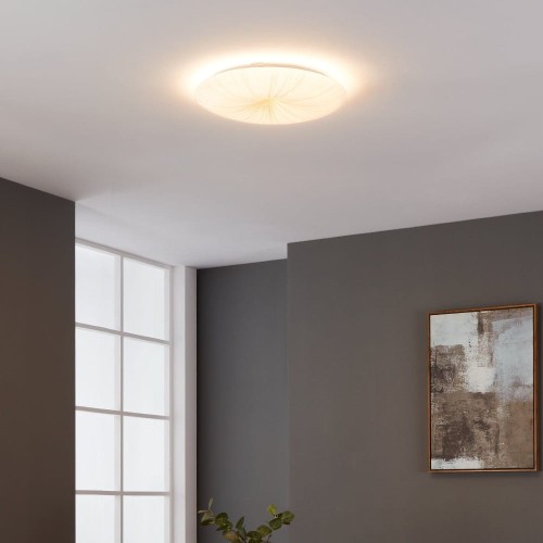 Okrągła lampa sufitowa LED NIEVES 1 19,5W z dekoracyjnym białym kloszem, zamontowana w nowoczesnym wnętrzu i emitująca ciepłe światło 3000K.