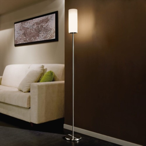 Lampa podłogowa TROY 3 z białym szklanym kloszem i smukłą podstawą w wykończeniu matowy nikiel, ustawiona przy łóżku i emitująca ciepłe światło.